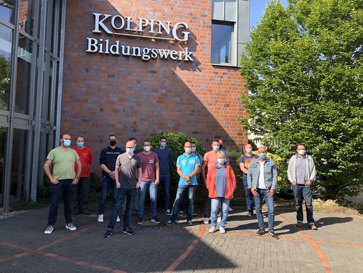 15 Quereinsteiger*innen stehen vor dem Gebäude der Kolping-Bahnakademie.